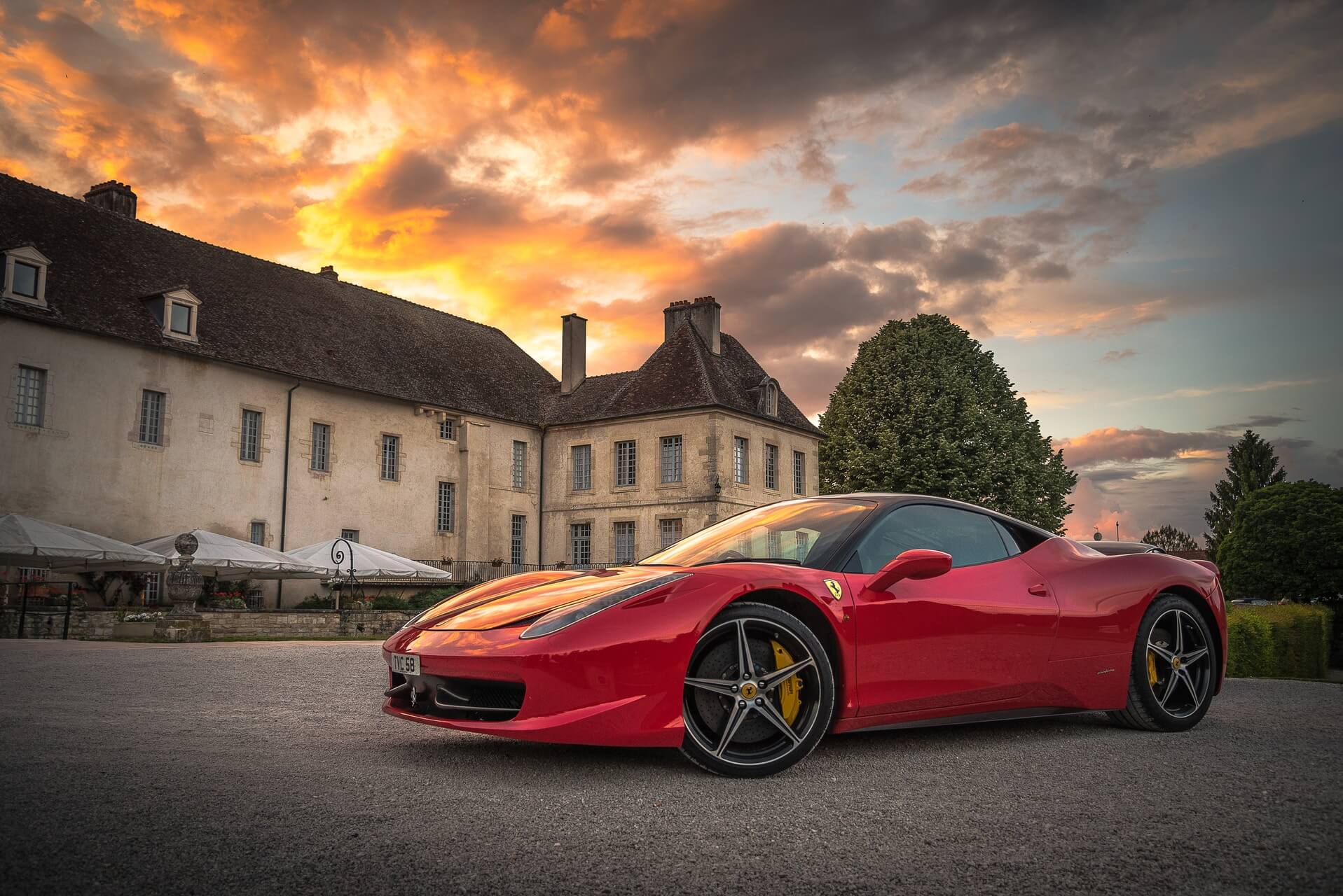 Tee McNeill McNeill Luxury Travel Photo by M red sports car on gray surface near building
